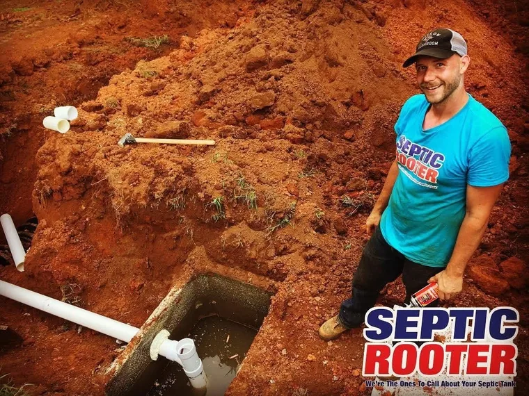 Smiling SepticRooter owner beside an excavated septic tank